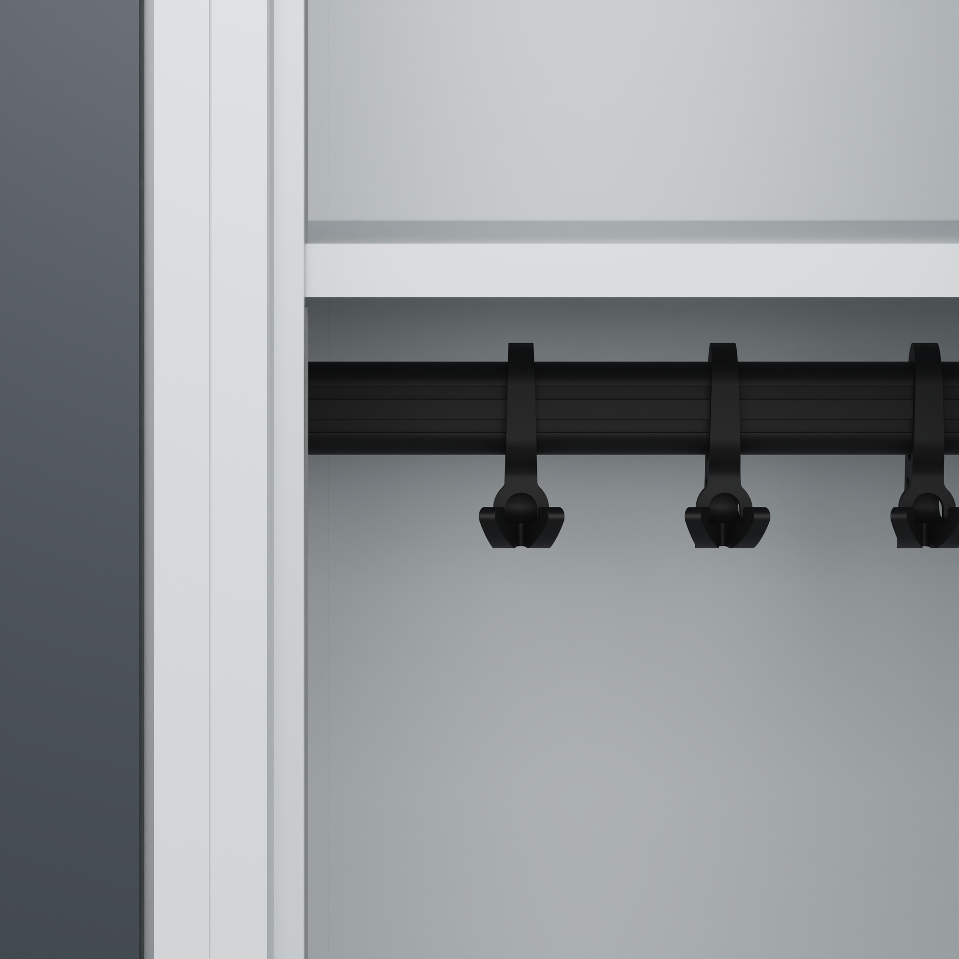 Schwarze Haken hängen an Kleiderstange in grauem Schrank.