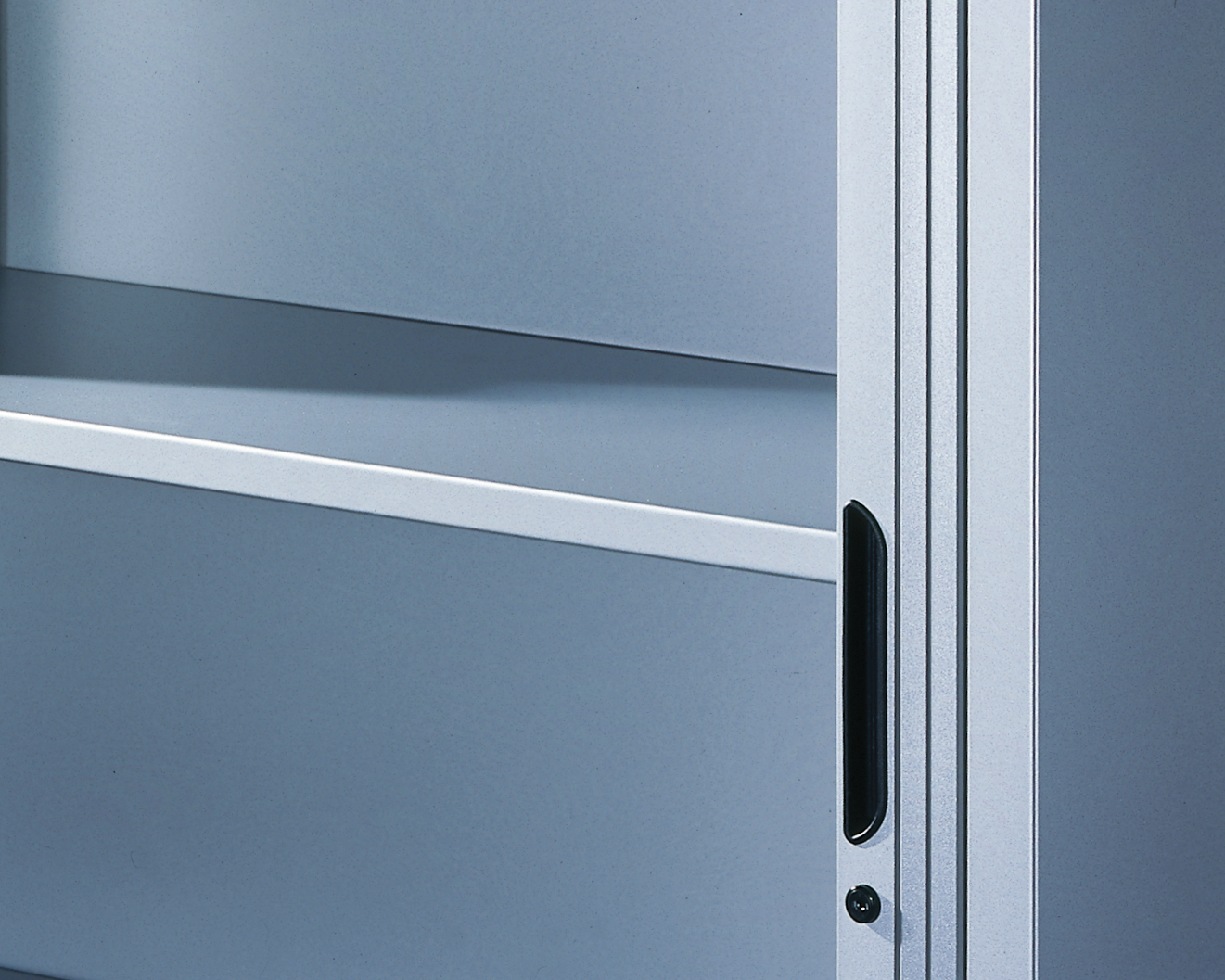 Metallschrank geöffnet in neutralem Raum, zeigt Griffdetail rechts.